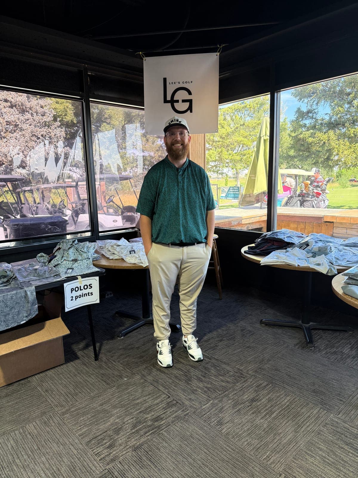 Hayden Lee standing beneath the Lee's Golf banner at an indoor golf course