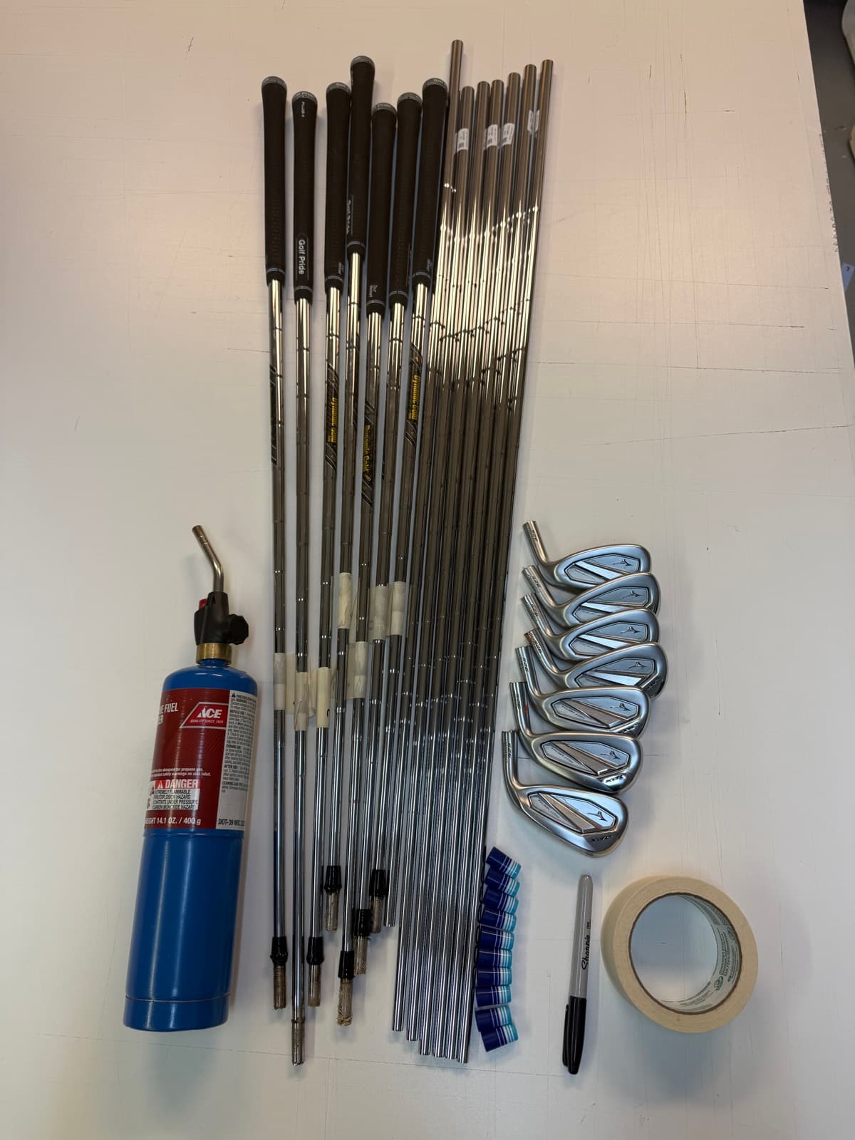 Build components laid out: shafts, iron heads, torch, tape, and grips