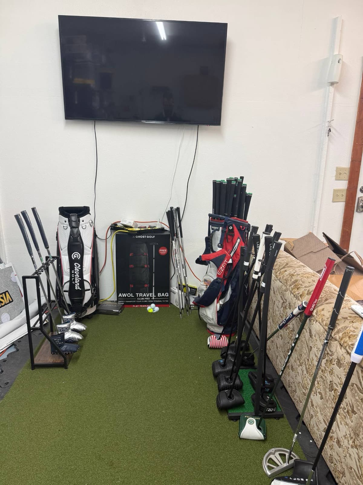 Fitting bay wall with mounted TV, club and putter racks