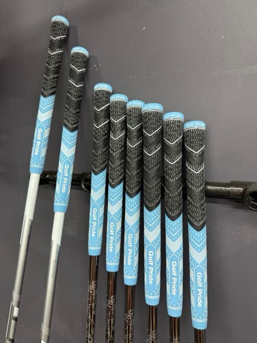 Six blue and black Golf Pride grips mounted on a wall rack