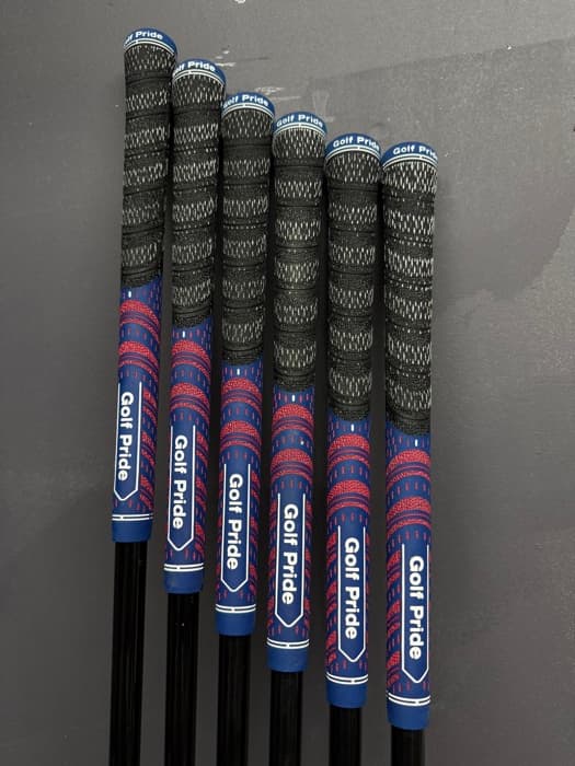 Six red and blue Golf Pride grips mounted on a wall rack